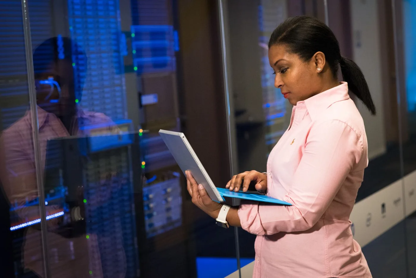 A software engineer reviewing data on a laptop in a server room